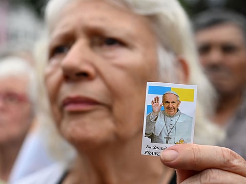 A woman holds a portrait of Pope Francis as she attends a mass for his healing in Constitution Squarein Buenos Aires.