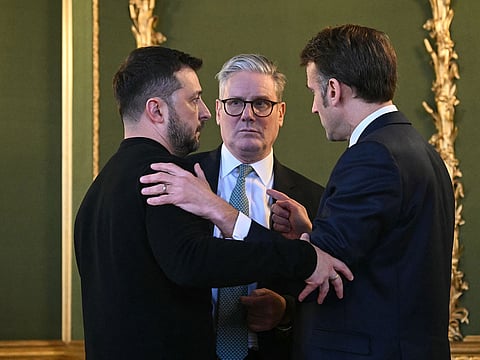 (L-R) Ukraine's President Volodymyr Zelensky, Britain's Prime Minister Keir Starmer and France's President Emmanuel Macron embrace after holding a meeting during a summit at Lancaster House in central London.