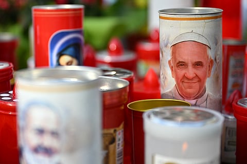 A candle bearing a portrait of Pope Francis is set at the feet of a statue of John Paul II outside the Gemelli hospital where Pope Francis is hospitalised in Rome on March 8, 2025.