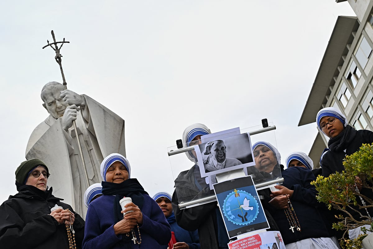 Nuns pray at the statue of John Paul II outside the Gemelli University Hospital where Pope Francis is hospitalized with pneumonia, in Rome.