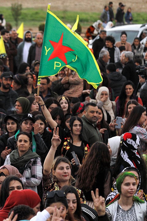 A woman holds a pennant of the Syrian-Kurdish Women