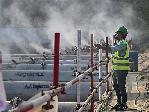 A worker adjusting an anti-smog dust suppression sprayer installed at a construction site in Lahore.