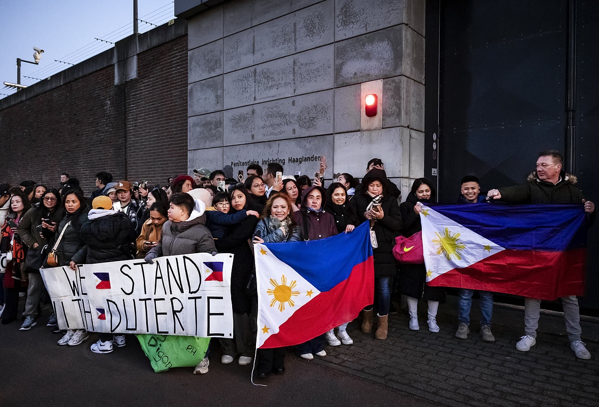 Protesters holding Filipino flags and a banner in support of former Philippine President Rodrigo Duterte gather outside the The Hague Penitentiary Institution prison.