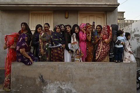 Hindu women watch the procession as they celebrate Hindu festival of Holi in Tharparkar district of the desert town of Mithi, south-eastern Pakistan, on March 13, 2025.