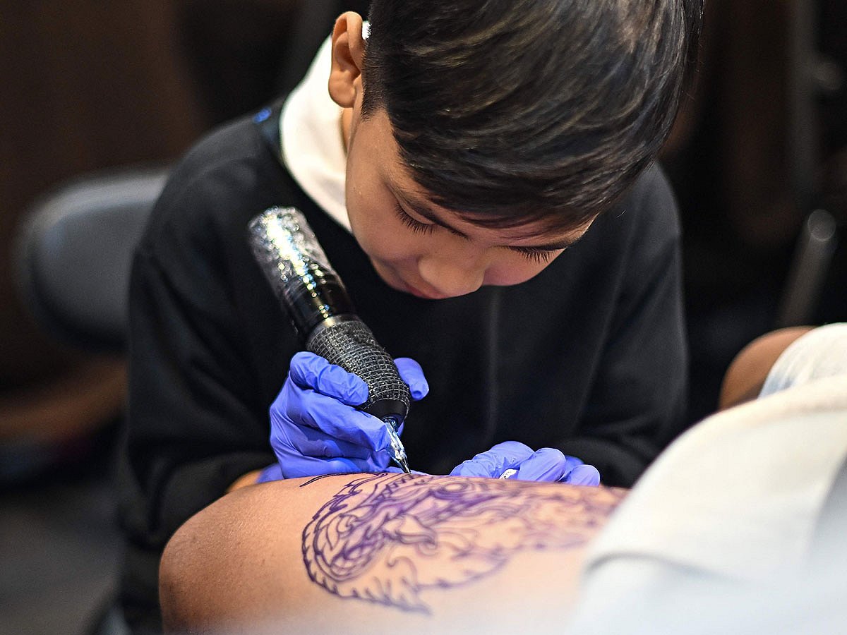 Nine-year-old Napat Mitmakorn, a Thai child tattoo artist works on his uncle’s tattoo at the 2025 Thailand Tattoo Expo in Bangkok.