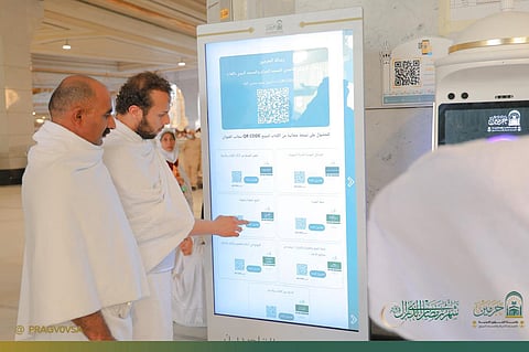 Pilgrims access digital screens and an AI-powered robot in the Grand Mosque in Ramadan.