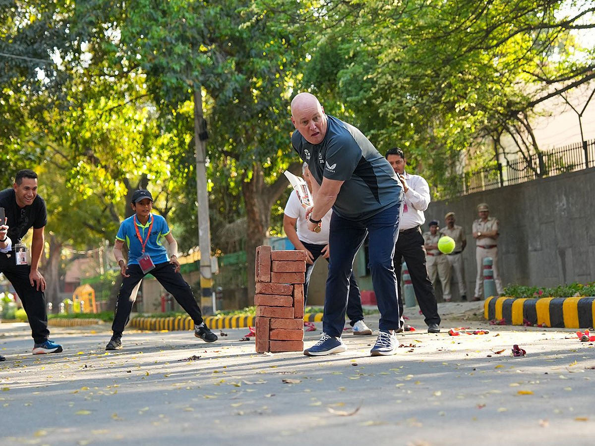 New Zealand Prime Minister Christopher Luxon playing cricket on the streets of New Delhi. 