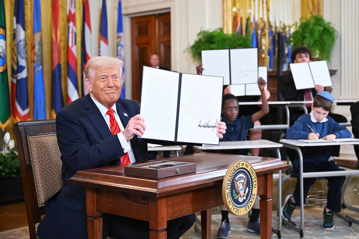 US President Donald Trump holds up an executive order after signing it in the East Room of the White house in Washington, DC, March 20, 2025.