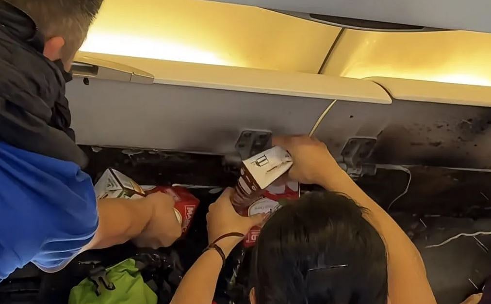 Crew and passengers work in tandem to douse a fire in the overhead locker of Hong Kong Airlines Flight 115 on March 20