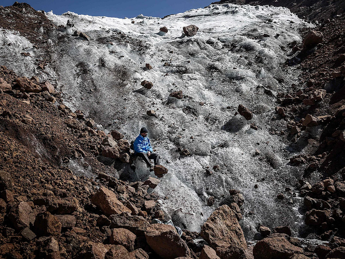 Professional mountaineer guide Charles Kibaki Muchiri, 50, observes the landscape while seated at the melting foot of Lewis Glacier near the summit of Mount Kenya