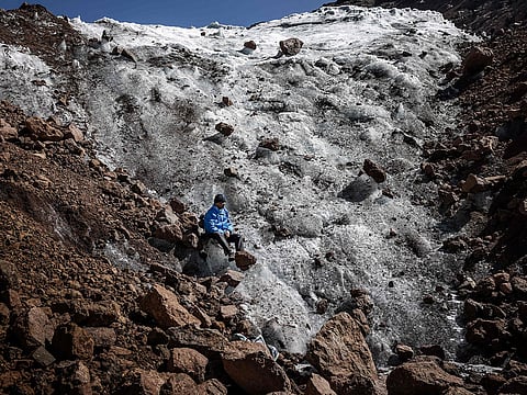 Professional mountaineer guide Charles Kibaki Muchiri, 50, observes the landscape while seated at the melting foot of Lewis Glacier near the summit of Mount Kenya