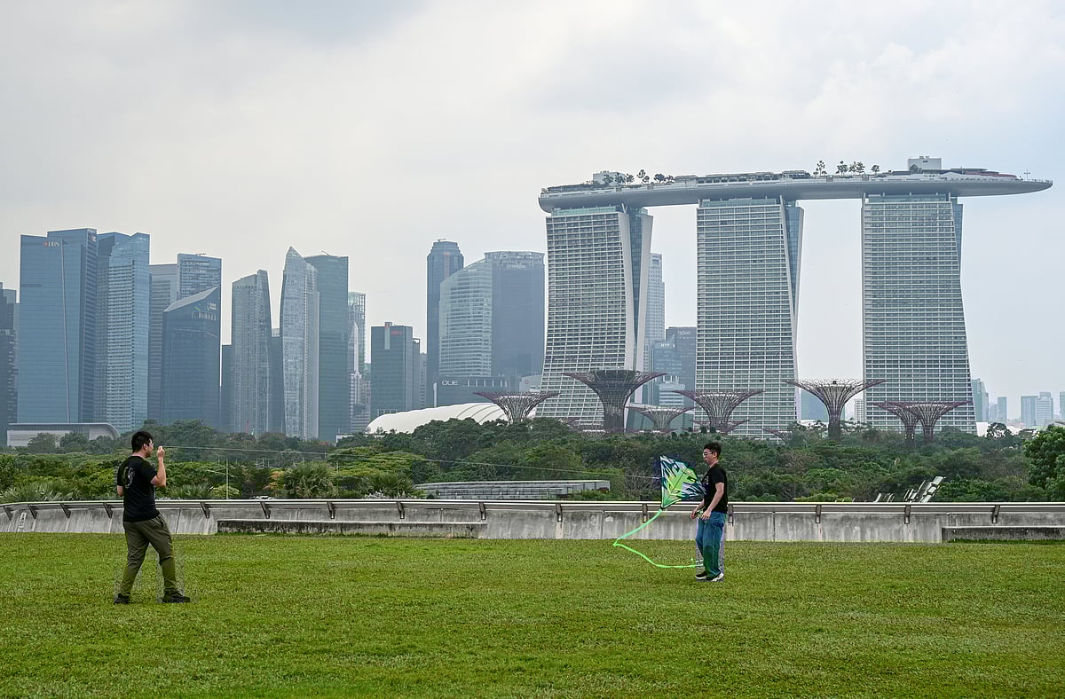 People fly a kite on the rooftop of Marina Barrage with a backdrop of the city skyline blanketed in haze amidst moderate levels of air pollution in Singapore on March 26, 2025.