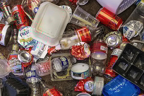 Recycled Coca-Cola bottles and cans rest among other recycled materials in a bin in Wye Mills, Maryland, on March 25, 2025, at a recycling drop centre.  