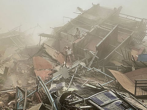 People inspect the debris of a collapsed building in Mandalay.