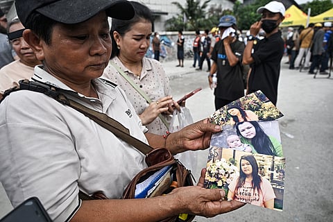 Wassana Phromma (L), from Thailand's northeastern province of Khon Kaen, shows photographs of her missing daughter Anusara, 35, at the site of an under-construction building collapse in Bangkok.