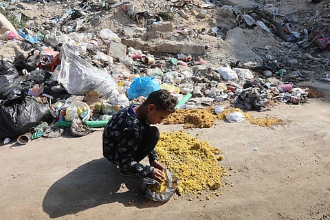 A Palestinian child collects food dropped on a street in Gaza City on March 30, 2025, during Eid Al Fitr. 