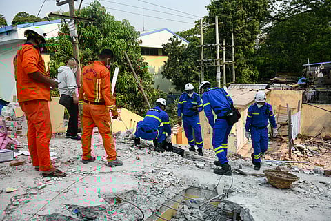 Chinese rescue team members (in blue) search for victims trapped in the rubble of a damaged temple in Mandalay on March 30, 2025, two days after an earthquake struck central Myanmar.