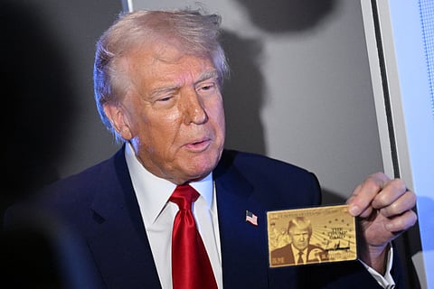 US President Donald Trump holds the $5 million dollar Gold Card as he speaks to reporters while in flight on board Air Force One, en route to Miami, Florida on April 3, 2025.