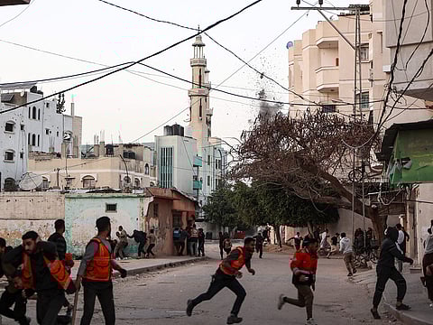 People and Palestinian rescuers run for cover as Israeli strike hits a school in the Al Tuffah neighbourhood in Gaza City on April 3, 2025.