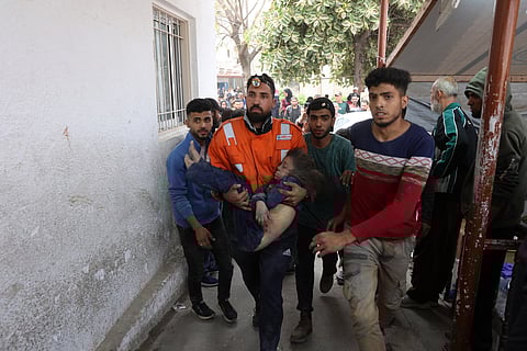 A Palestinian rescuer carries the body of a child killed in an Israeli strike on a residential area in Gaza City's Shujaiyya neighbourhood.