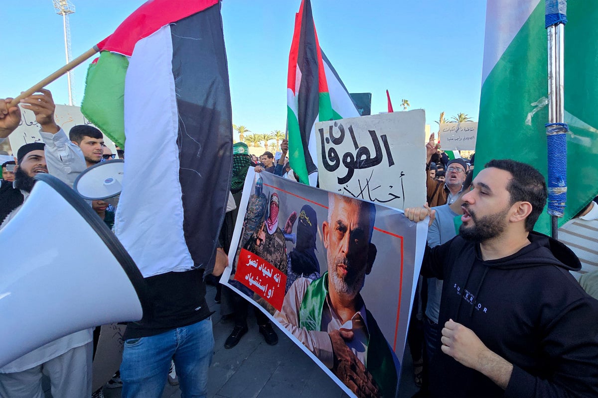 People wave Palestinian flags and hold a portrait of slain militant Hamas group commander Yahya Sinwar during a demonstration in support of the people of Gaza at Martyrs Square in Tripoli on Aptil 8, 2025.  