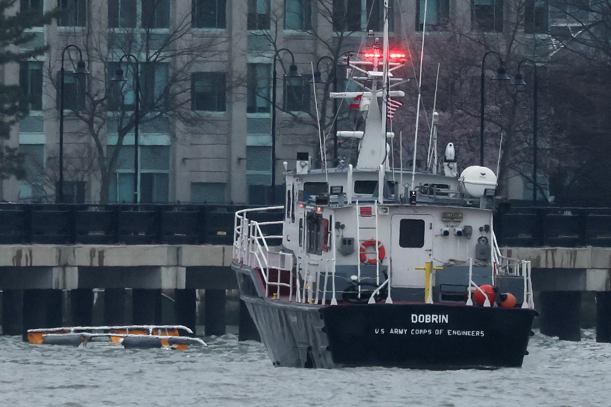 A helicopter's landing skids (L) are seen in the water next to a US Army Corps of Engineers boat off the shore of Hoboken, New Jersey, as seen from New York after it crashed into the Hudson River on April 10, 2025.
