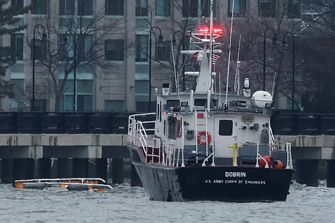 A helicopter's landing skids (L) are seen in the water next to a US Army Corps of Engineers boat off the shore of Hoboken, New Jersey, as seen from New York after it crashed into the Hudson River on April 10, 2025.