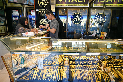 An employee helps a customer to buy gold jewellery at a market place on April 14, 2025.