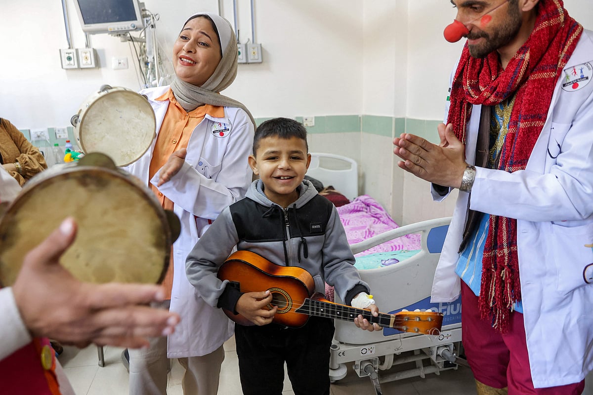 A boy plays a ukelele as he stands with members of the Gaza Circus School relief team as they perform for children in a ward at the Abdelaziz al-Rantisi Paediatric Hospital in Gaza City on April 15, 2025.
