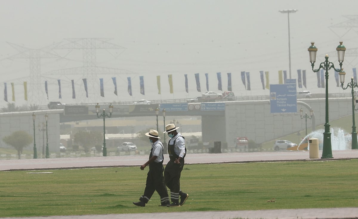 Workers wearing masks in dusty weather with low visibility  in Sharjah.