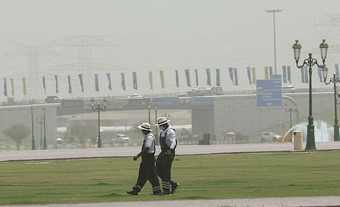 Workers wearing masks in dusty weather with low visibility in Sharjah.