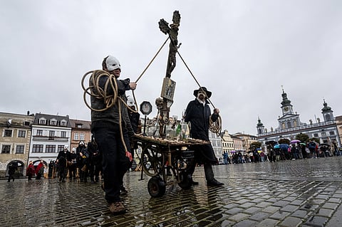 Participants wearing white masks push a carriage with a crucifix during an Easter traditional procession to mark Good Friday