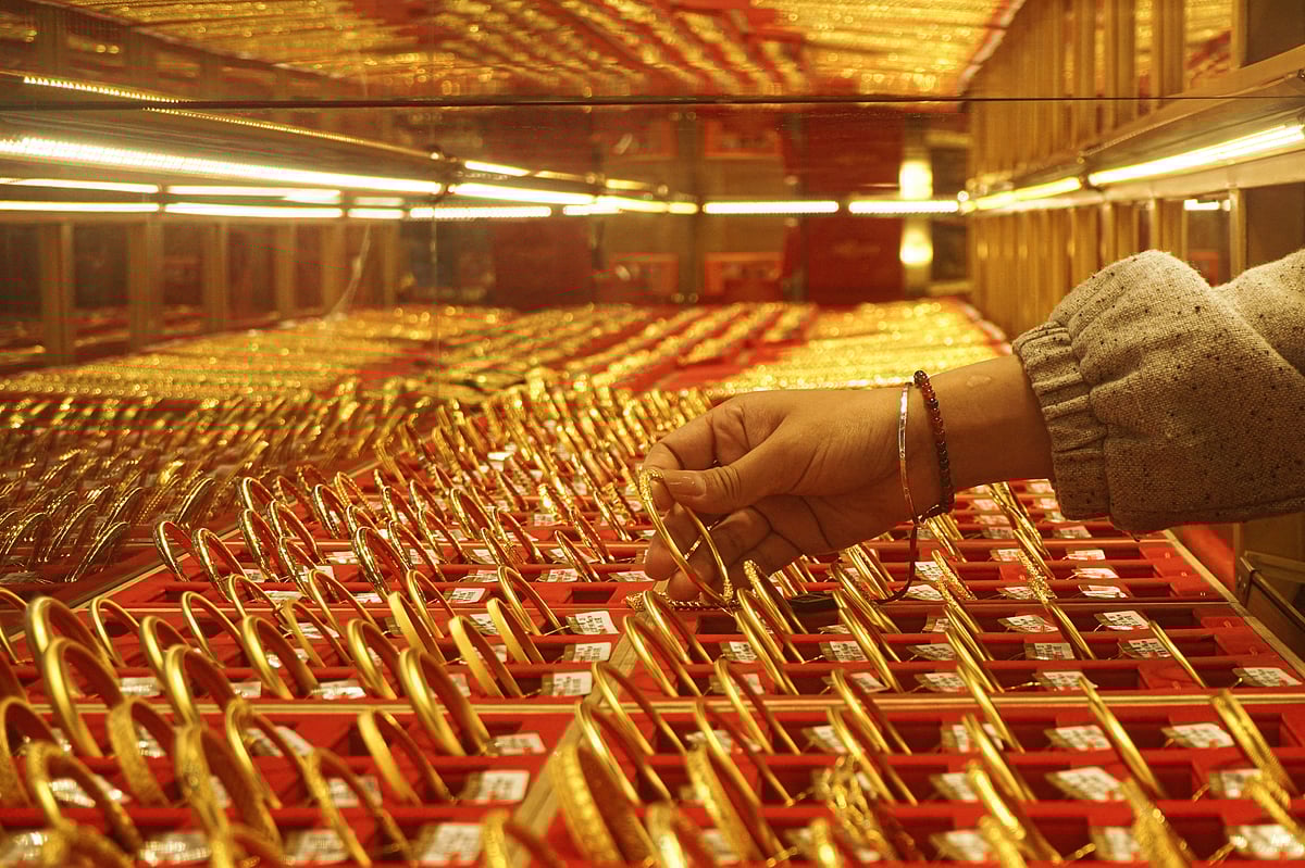 A shop assistant displays gold bangles for sale at a gold shop in Hangzhou, in eastern China's Zhejiang province on April 22, 2025.
