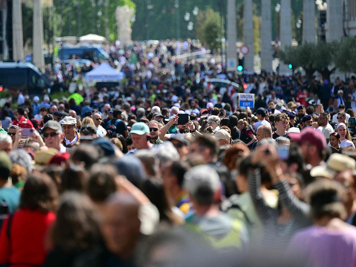 A crowd of pedestrians walking on Via della Conciliazione near the Vatican in Rome, following the Pope's death.