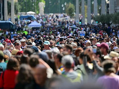 A crowd of pedestrians walking on Via della Conciliazione near the Vatican in Rome, following the Pope's death.