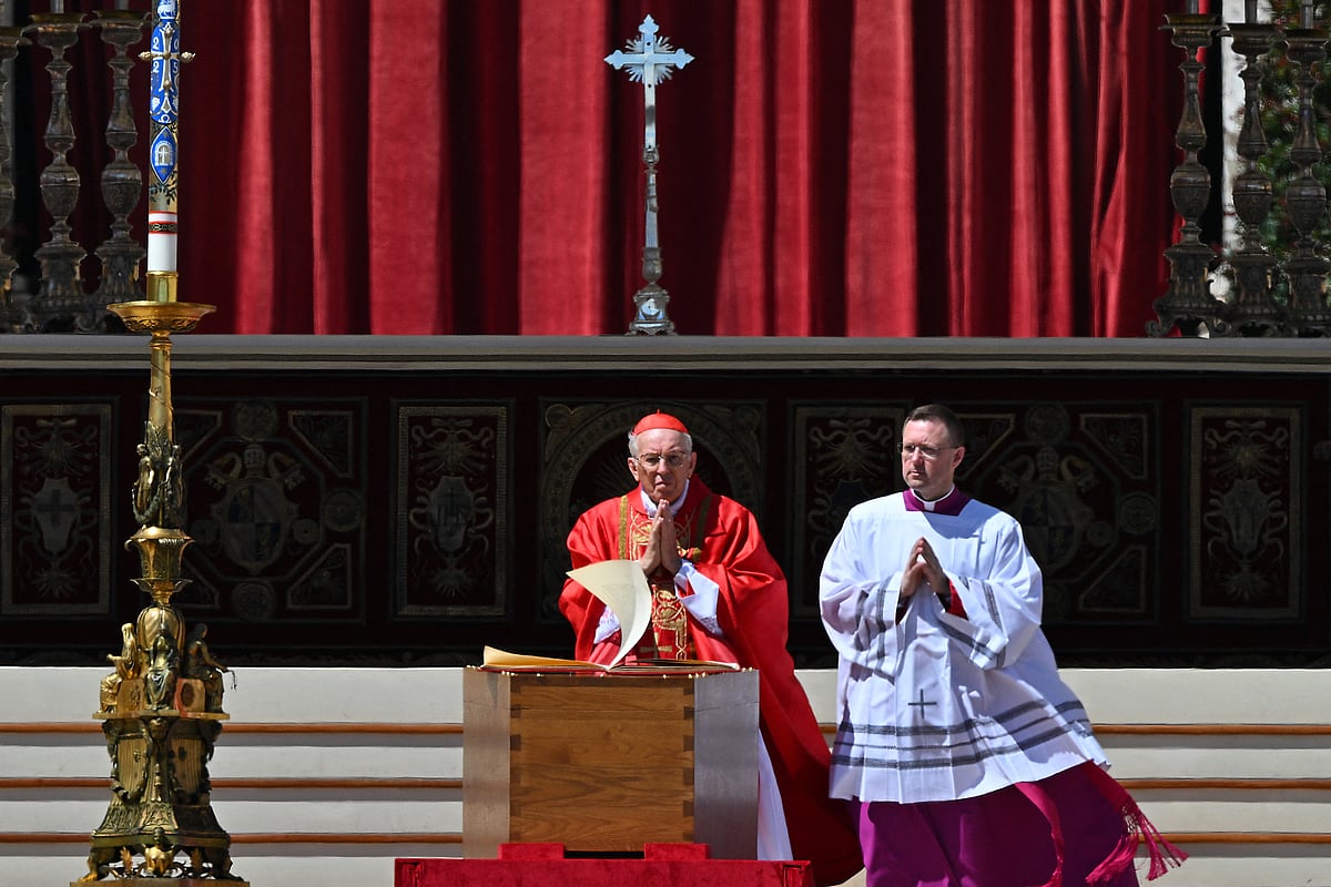 The wind flips the pages of the Book of Gospels as Italian cardinal Giovanni Battista Re (L) officiates near the coffin of late Pope Francis during the funeral ceremony at St Peter's Square in the Vatican, on April 26, 2025.