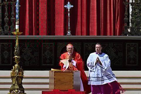 The wind flips the pages of the Book of Gospels as Italian cardinal Giovanni Battista Re (L) officiates near the coffin of late Pope Francis during the funeral ceremony at St Peter's Square in the Vatican, on April 26, 2025.
