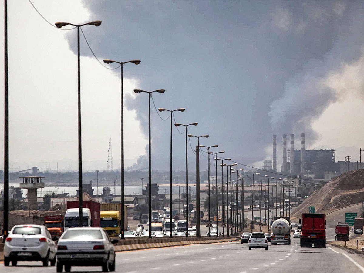 A thick plume of smoke billows as motorists drive their vehicles along a highway near the source of an explosion at the Shahid Rajaee port dock southwest of Bandar Abbas in the Iranian province of Hormozgan.
