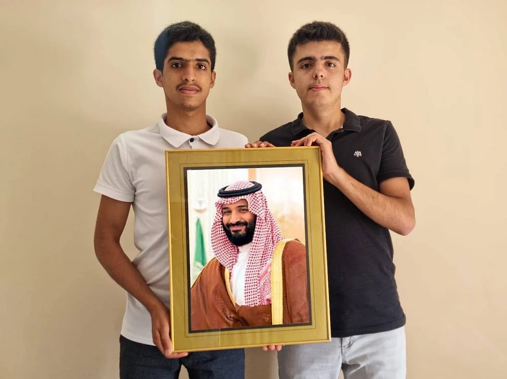 Yaqoub Al Manjam (left) and Turkish Ali hold a portrait of Saudi Crown Prince Mohammed bin Salman. 