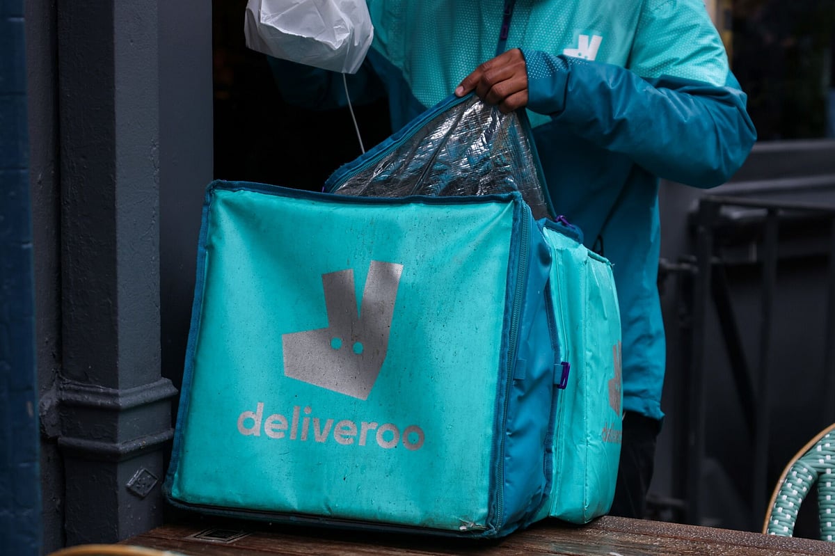 A Deliveroo courier collects an order from a restaurant in Soho, London