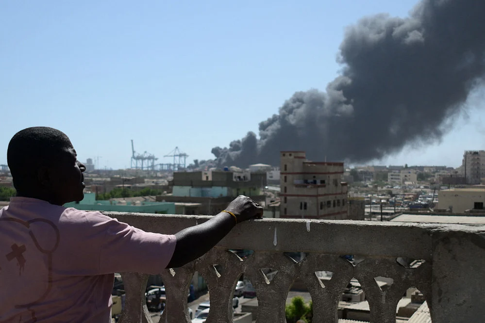  A man watches as smoke billows after a drone strike on the port of Port Sudan on May 6, 2025.  