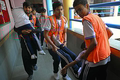 Students participate in an emergency mock drill as part of the nationwide civil defence mock drill at a school in New Delhi on May 7, 2025, as border tensions surge. In a sweeping exercise to assess emergency readiness, India conducted full-scale civil defence mock drills nationwide on Wednesday, May 7. The Ministry of Home Affairs ordered the drills amid escalating tensions with Pakistan, directing all states and union territories to evaluate preparedness for “new and complex threats.”