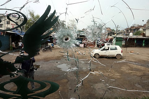 Residents are seen through the windshield of a bus damaged by a cross-border shelling between India and Pakistan in Poonch.