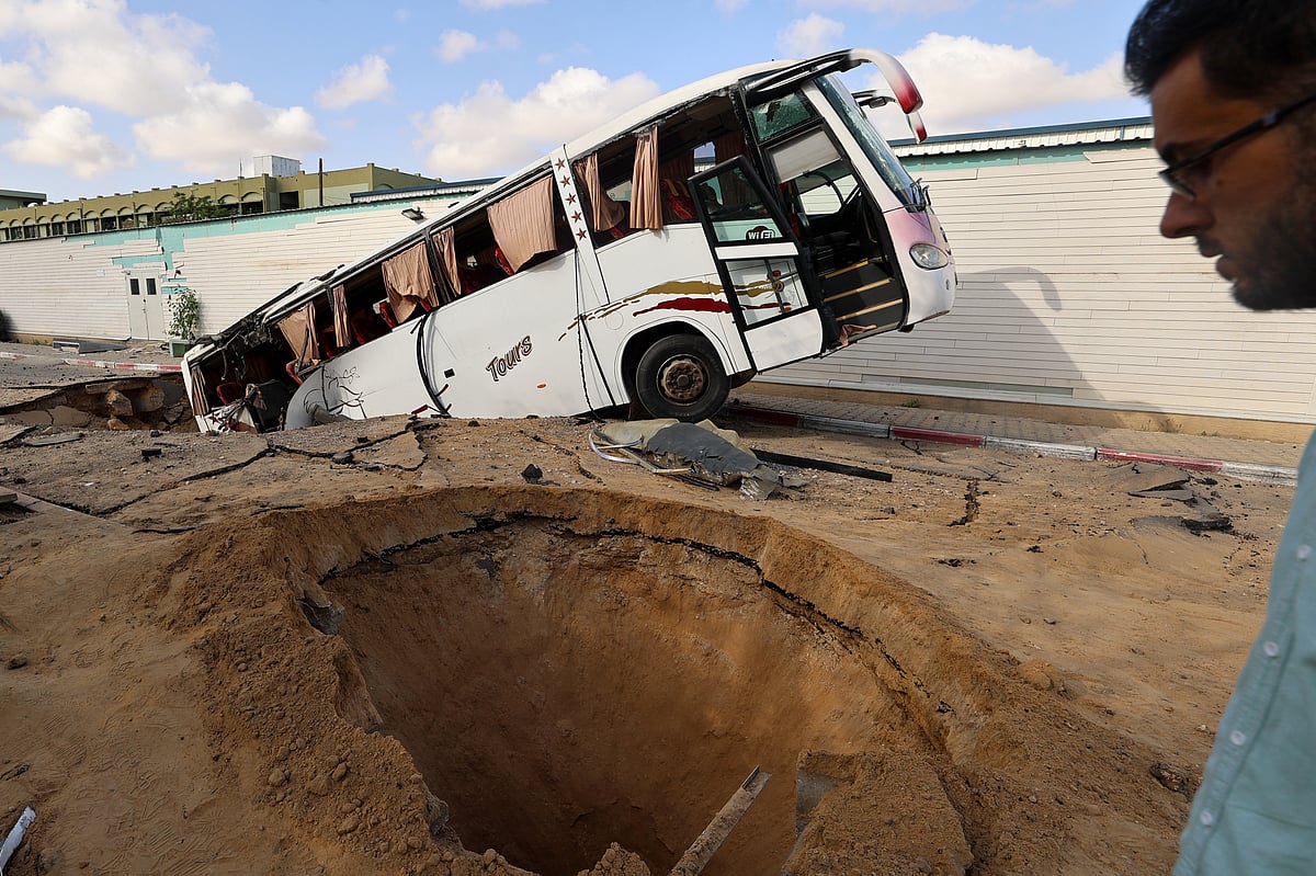 A man walks past a bus inside a crater in the aftermath of an Israeli strike in Khan Yunis in the southern Gaza Strip on May 14, 2025.