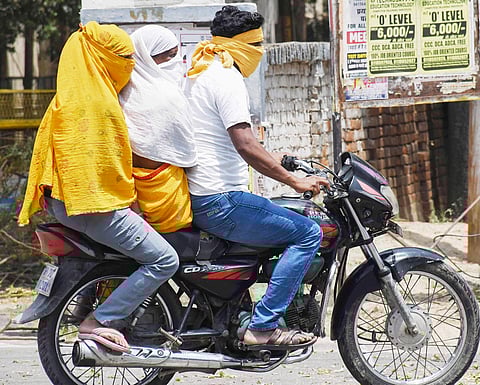 Commuters cover their faces to protect themselves from scorching heat on a hot summer day in Prayagraj.