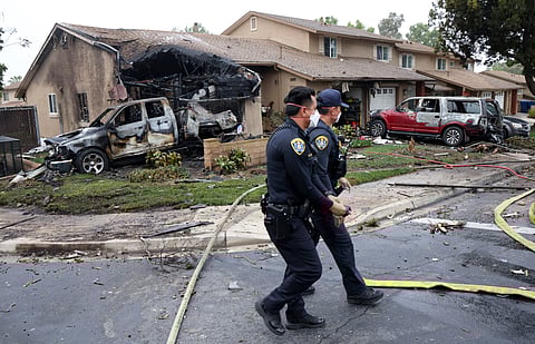 Police officers search the site where a small plane crashed on a San Diego, California, residential street on May 22, 2025