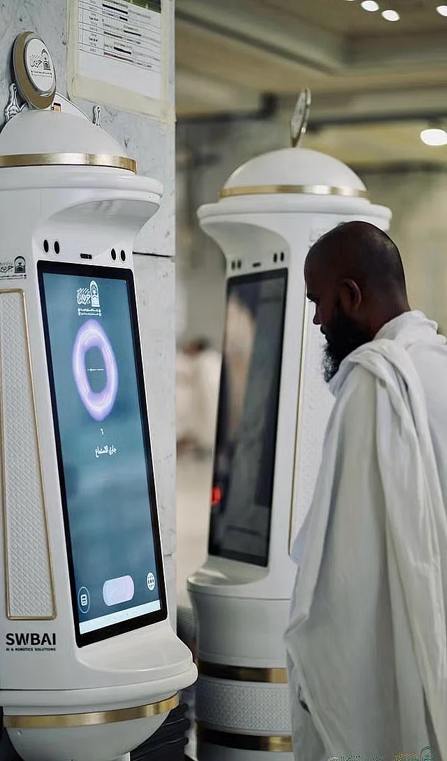 A Muslim worshipper seeks help from the Manara robot in the Grand Mosque in Mecca.  