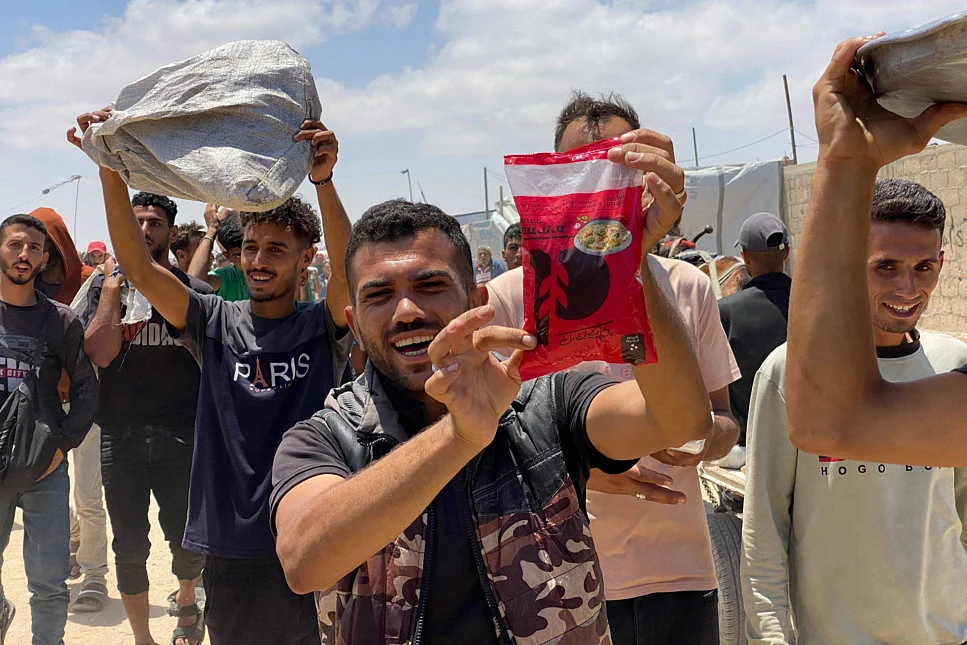 Displaced Palestinians react as they display items received from an aid distribution center in Khan Yunis in the southern Gaza Strip on May 28, 2025.  