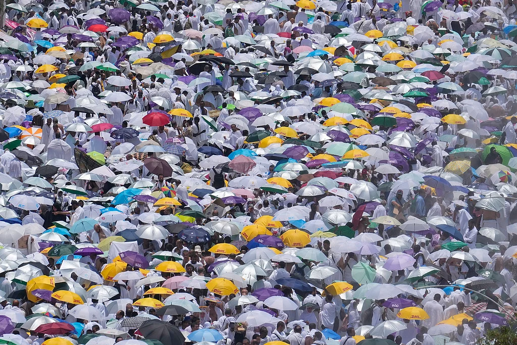 Pilgrims use umbrellas to shield themselves from the sun as they gather outside Nimrah Mosque to offer the noon prayers in Arafat. 