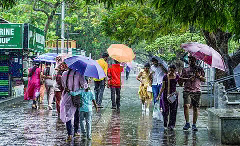 People walk through heavy rain at the Marine Drive walkway in Kochi, Kerala, India.